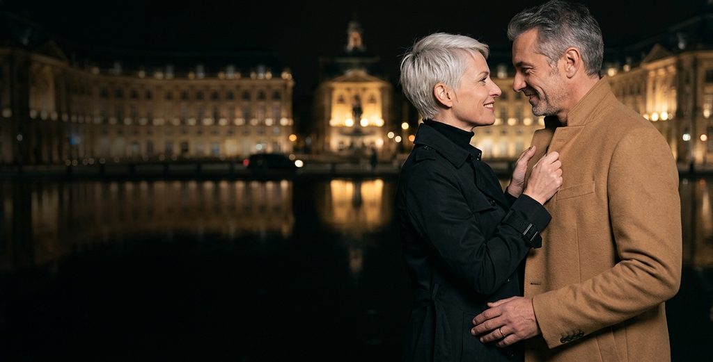 Rencontre adultère à Bordeaux : couple devant le miroir d’eau et la place de la Bourse la nuit